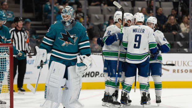 A dejected Kaapo Kahkonen with Canucks players celebrating behind him